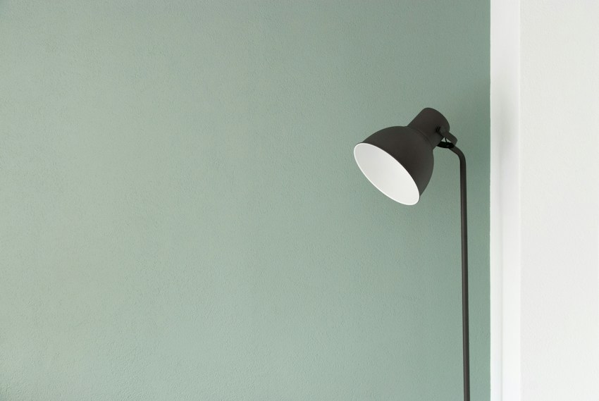 A simple black floor lamp against a softly lit wall